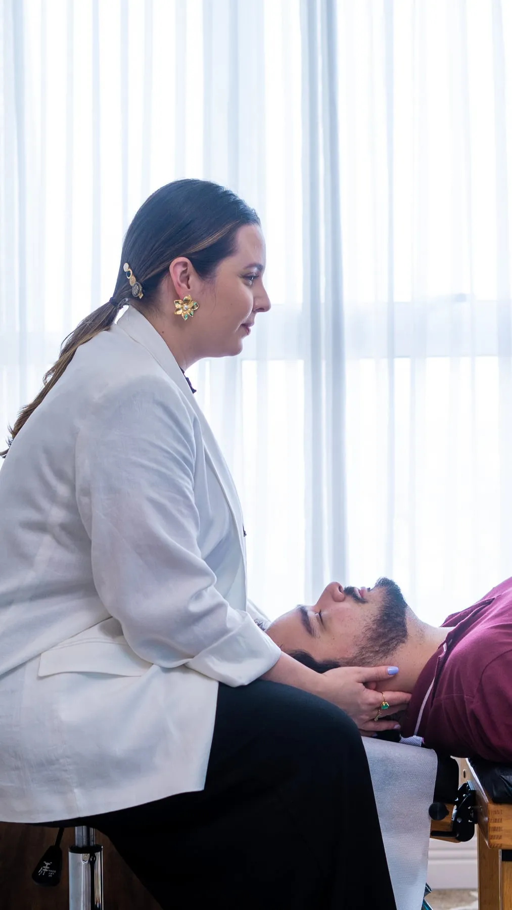 Dra. Vitória ajustando um paciente deitado na maca, no consultório